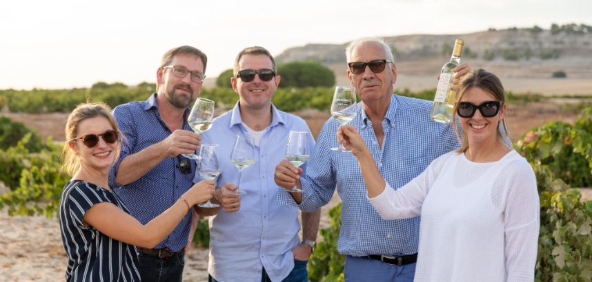 Gruppe von Menschen, die draußen Wein anstoßen.